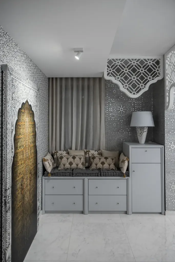Angolo relax con cassettiere su misura, cuscini decorativi e dettagli orientali in una cabina armadio di lusso.