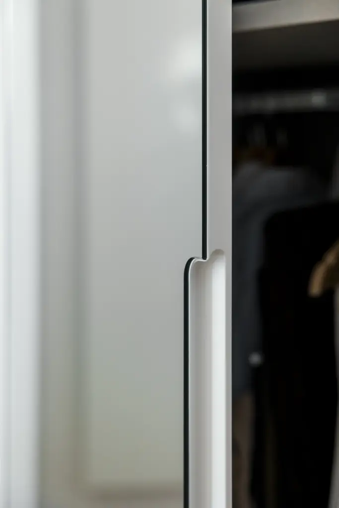 Dettaglio di anta armadio bianca con elegante maniglia a gola, design minimalista e apertura ergonomica.