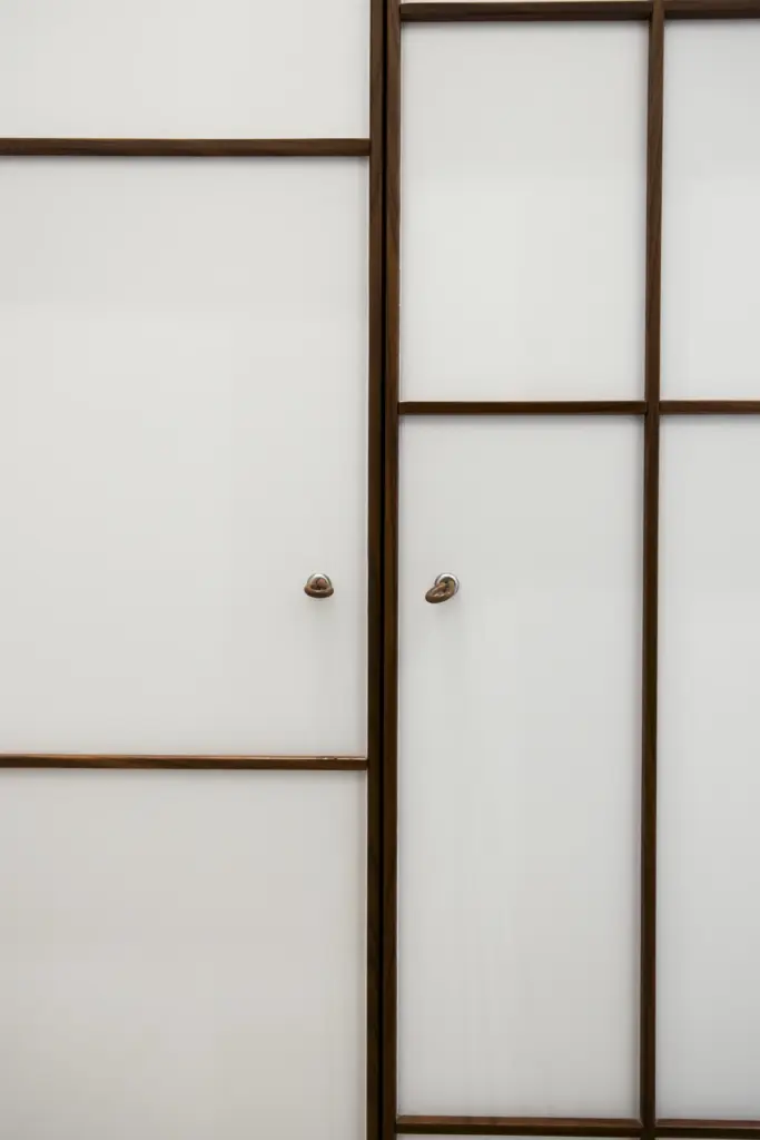 Dettaglio di ante in vetro opaco con struttura a griglia in legno e maniglie moderne.