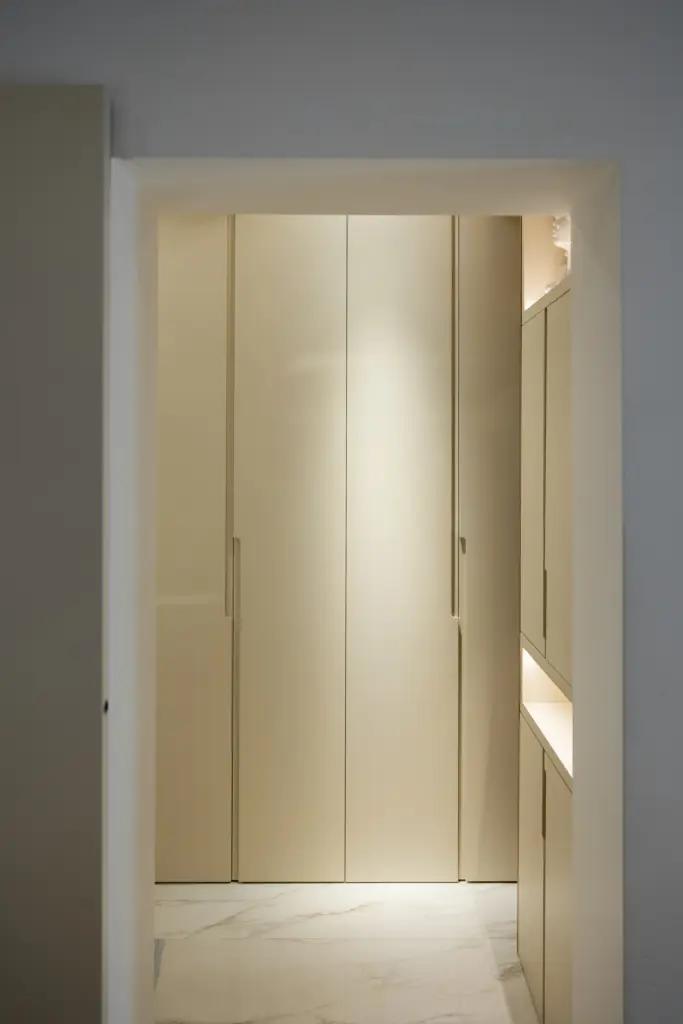 Armadi a tutta altezza su misura in corridoio moderno con finitura chiara e illuminazione integrata.