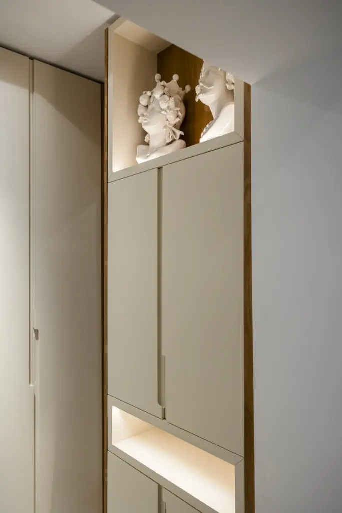 Armadio su misura in finitura chiara con nicchia decorativa e illuminazione integrata.