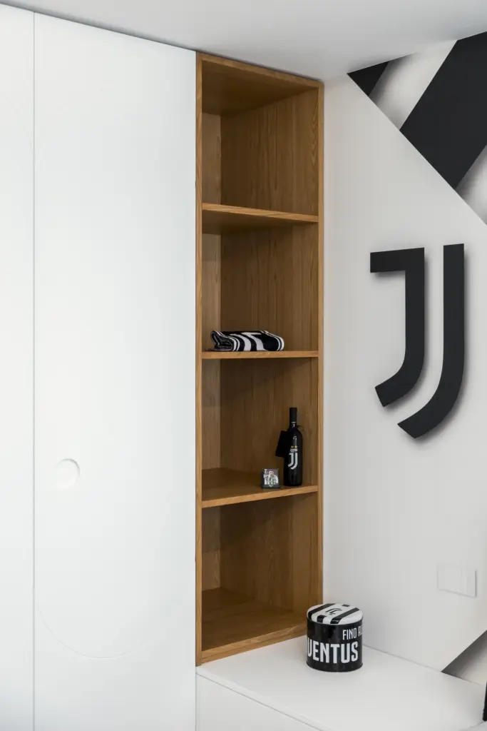 Dettaglio di una camera moderna a tema Juventus con libreria in legno e pareti bianche.