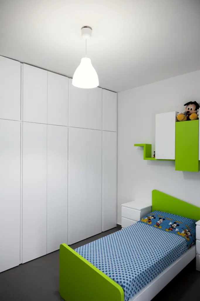 Cameretta per bambini con letto singolo verde e grande armadio bianco su misura.