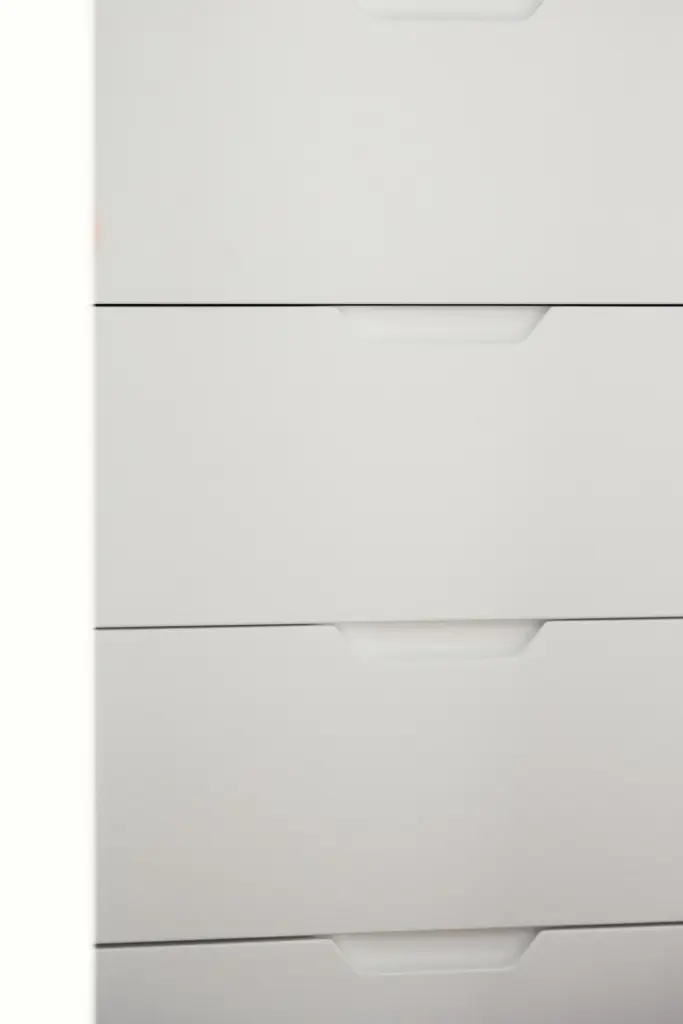 Dettaglio di cassetti bianchi con maniglie integrate a incavo.
