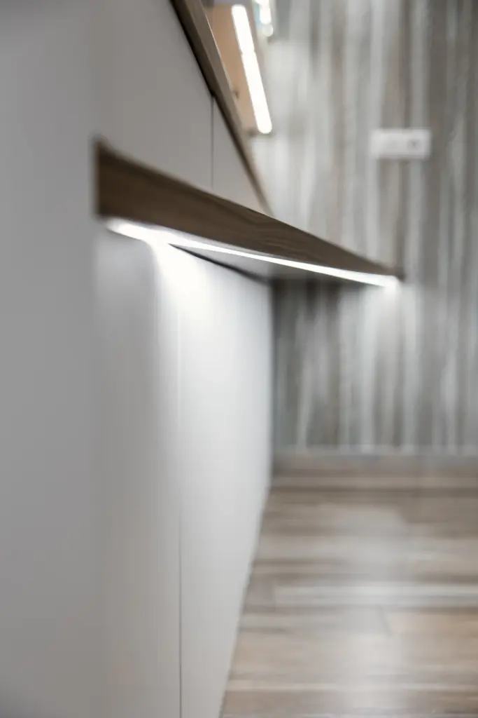 Cassettiera moderna bianca con linee minimaliste, accompagnata da uno specchio ovale di design e decorazioni delicate.
