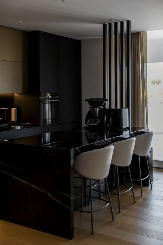 Cucina moderna con bancone in marmo nero lucido e sgabelli imbottiti chiari