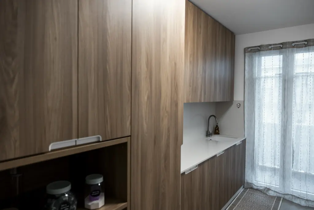 Cucina dal design contemporaneo con mobili in legno naturale, piano bianco e lavandino integrato.