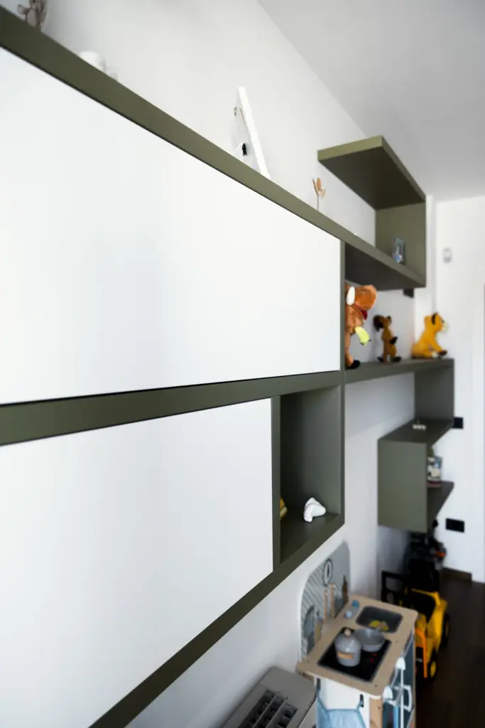 Vista ravvicinata di mobili sospesi moderni verde oliva in una cameretta per bambini.