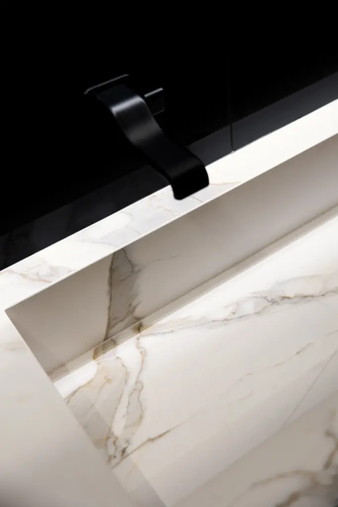 Lavabo integrato in marmo bianco venato con rubinetteria nera a parete, design moderno ed elegante
