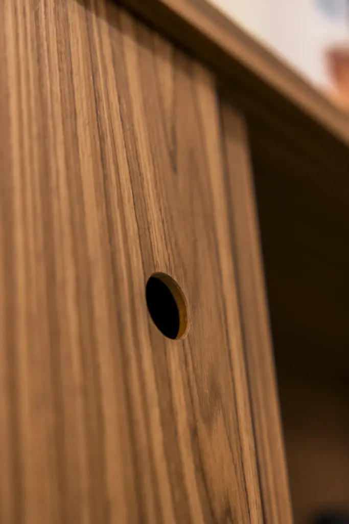 Primo piano della maniglia a incasso su anta scorrevole in legno di noce.
