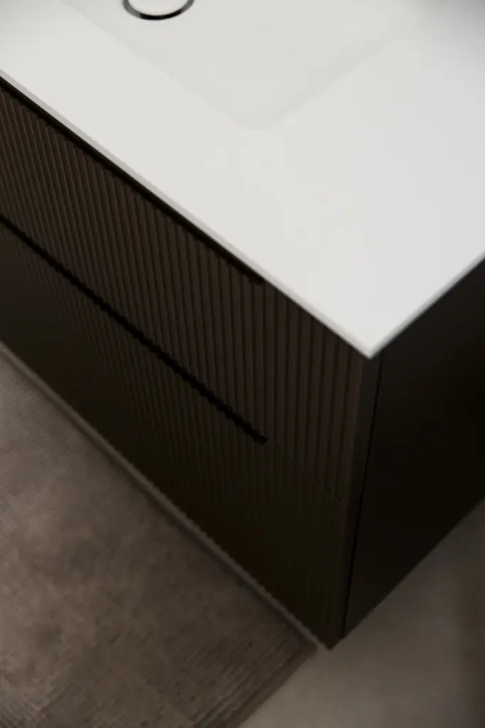 Vista ravvicinata del mobile bagno con cassetti scanalati e piano in solid surface bianco opaco