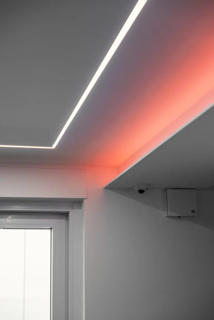 Dettaglio di un soffitto moderno con illuminazione LED rossa integrata e videocamera di sorveglianza.