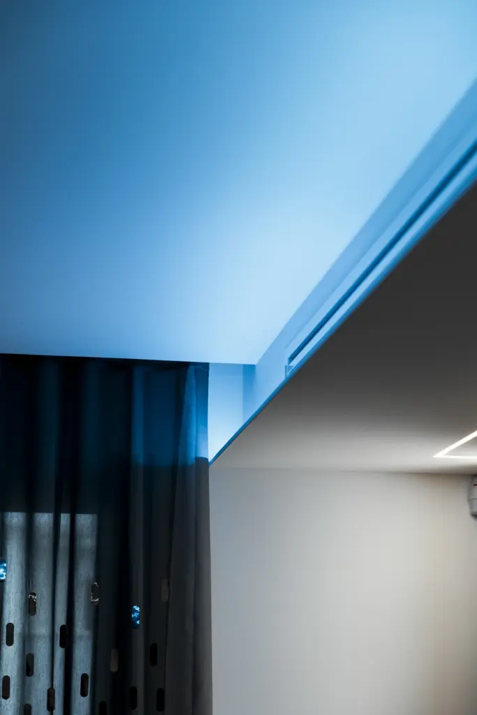 Dettaglio di illuminazione a LED blu integrata nel soffitto di un ambiente moderno.