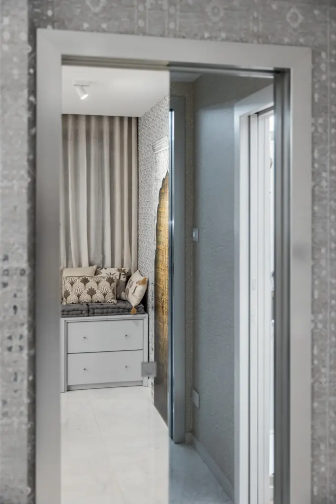 Vista dell'ingresso di una cabina armadio elegante con mobili su misura e decorazioni di pregio.
