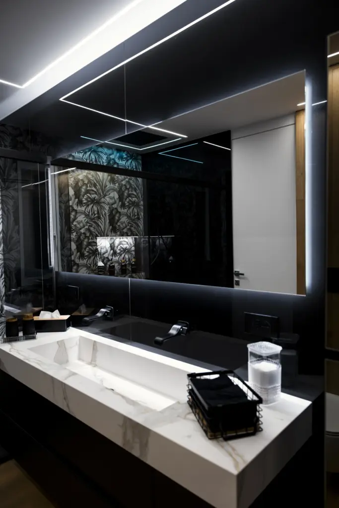 Lavabo in marmo bianco venato con doppia rubinetteria nera opaca e grande specchio con illuminazione LED integrata