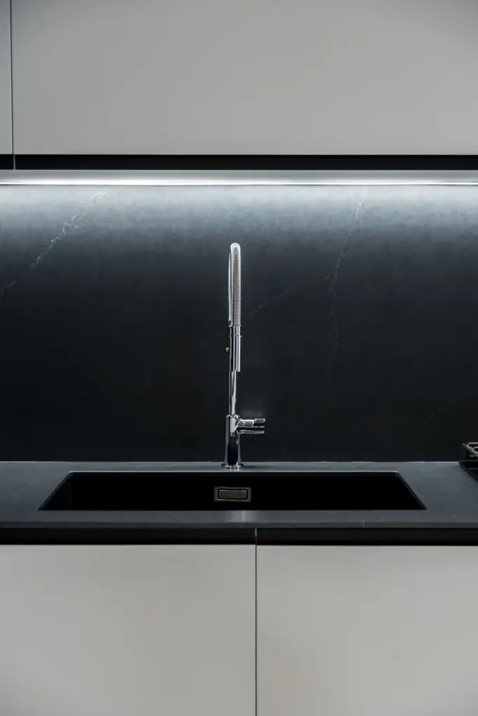Lavello da cucina moderno con top scuro, rubinetto in acciaio cromato e retroilluminazione a LED.