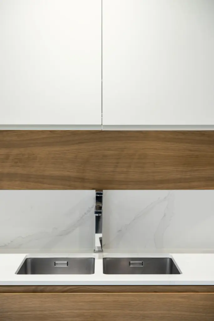 Lavello a doppia vasca in acciaio inox integrato su piano cucina effetto marmo.
