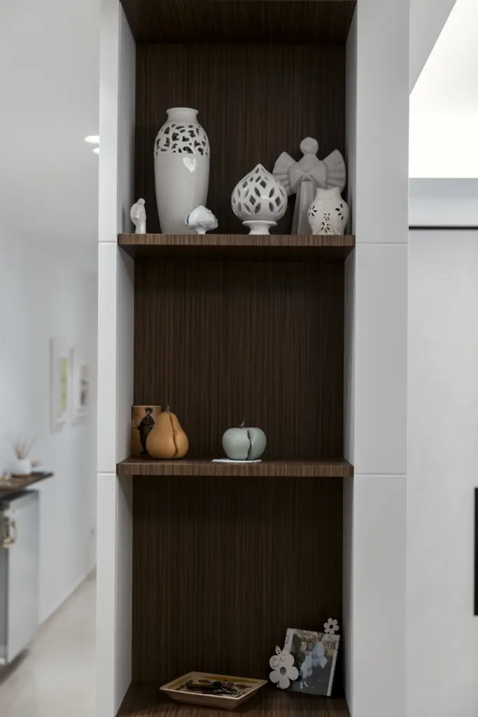 Libreria su misura in bianco e legno con oggetti decorativi.