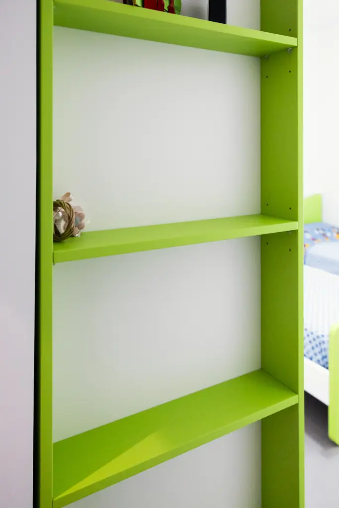 Vista ravvicinata di una libreria verde su misura integrata in una cameretta moderna.