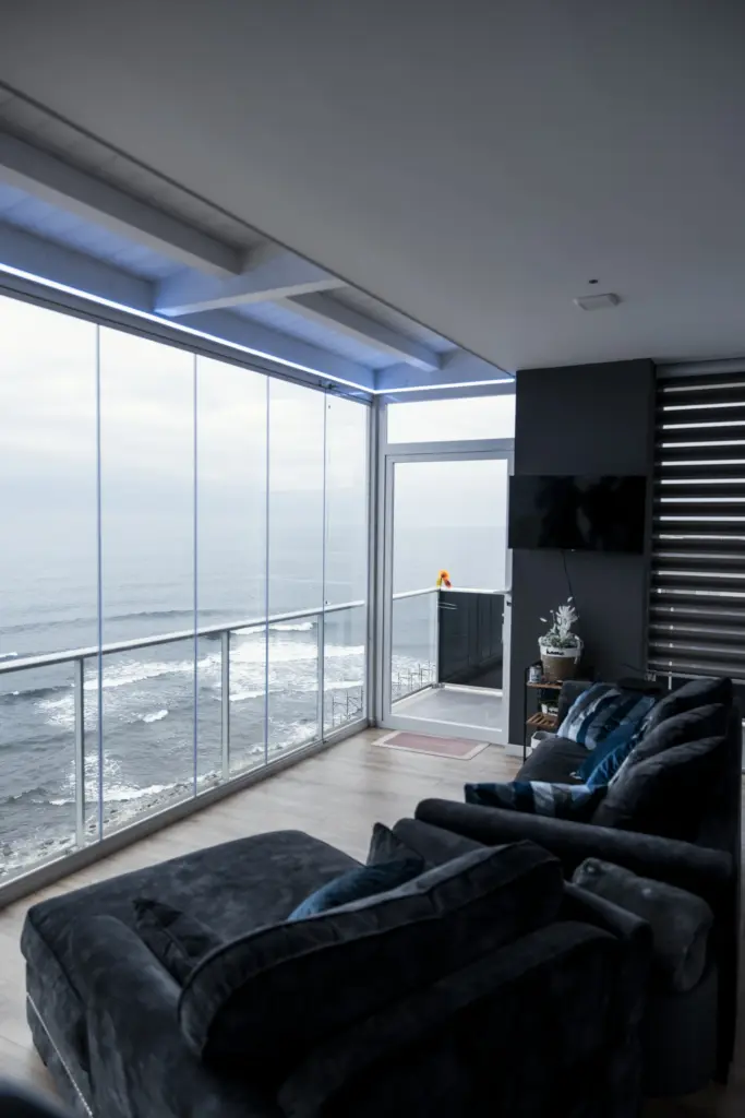 Zona living con divani scuri, vetrata panoramica sul mare e accesso al balcone, design moderno