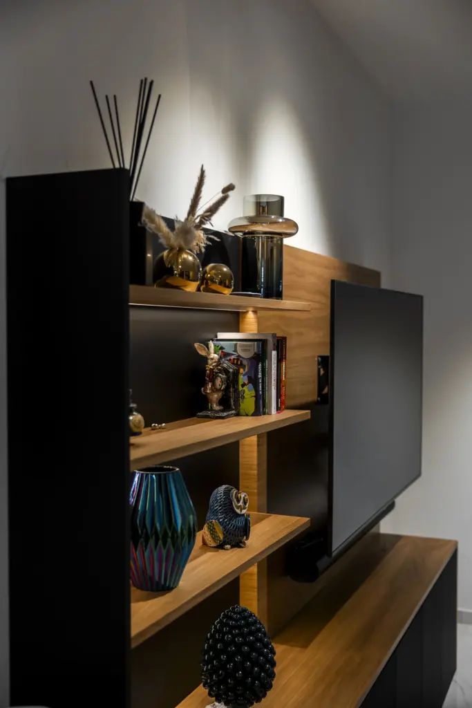 Mensole in legno naturale con decorazioni e libri su parete attrezzata moderna in soggiorno.