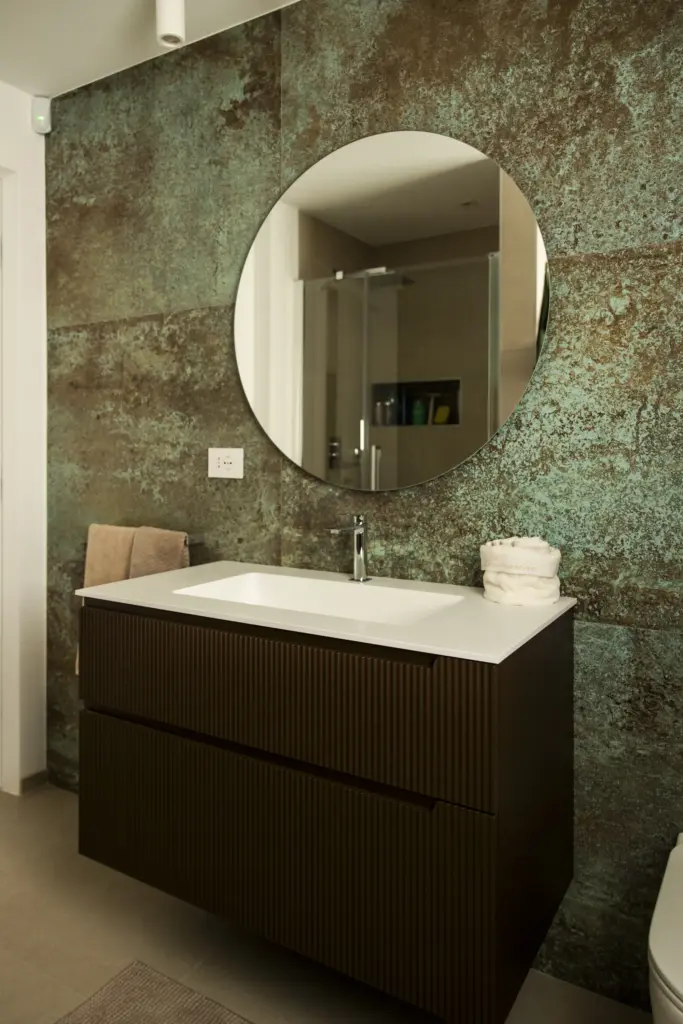 Mobile bagno sospeso con lavabo integrato e parete con finitura effetto rame ossidato, design moderno
