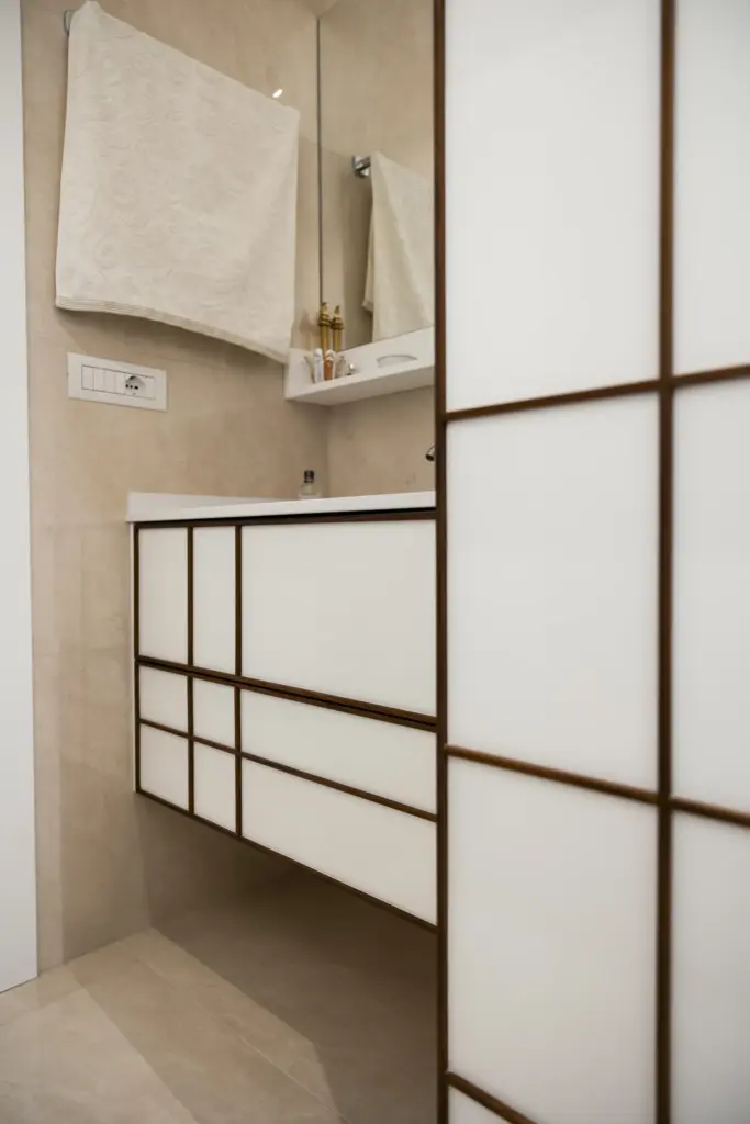 Mobile bagno sospeso con pannelli in vetro opaco e struttura a griglia in legno.
