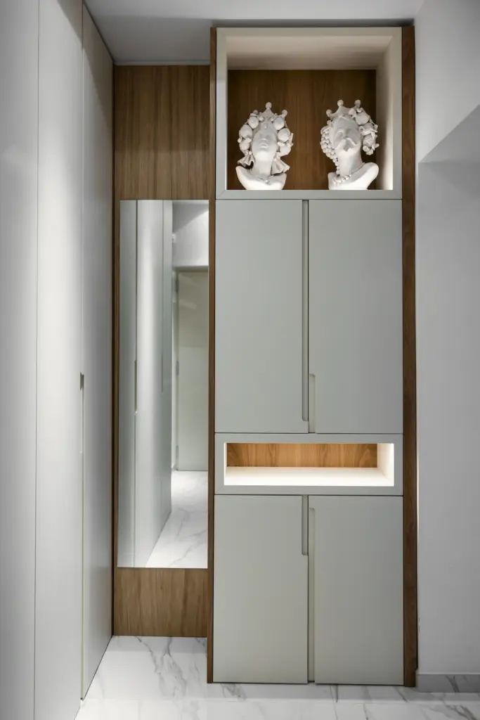 Mobile su misura per ingresso con struttura in legno, ante laccate e nicchia illuminata.