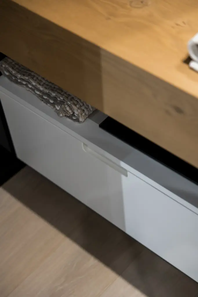 Mobile bianco con top in legno naturale e maniglia integrata minimalista.
