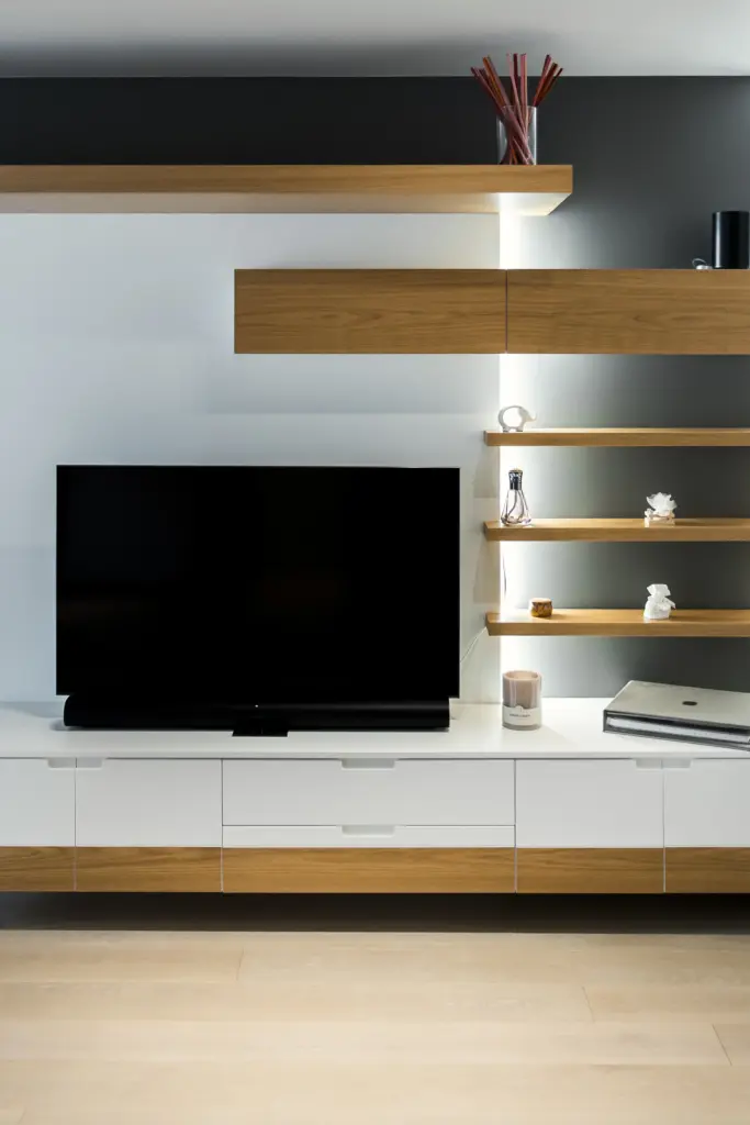 Parete attrezzata moderna con finiture in legno naturale e bianco, TV e mensole luminose.