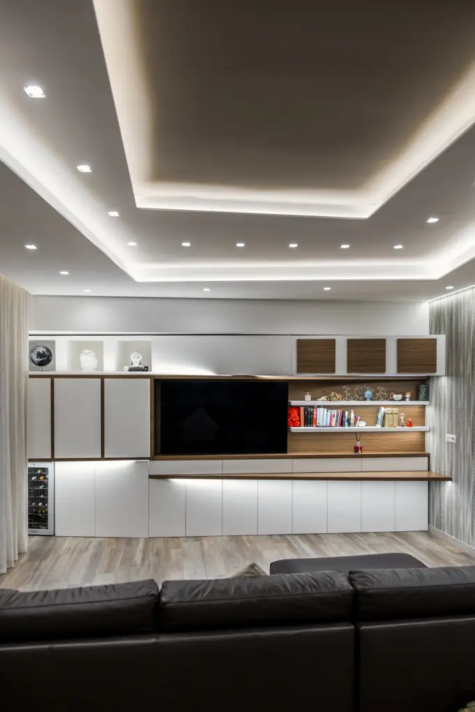 Parete attrezzata moderna con mobile TV integrato, libreria e pensili bianchi e in legno naturale.
