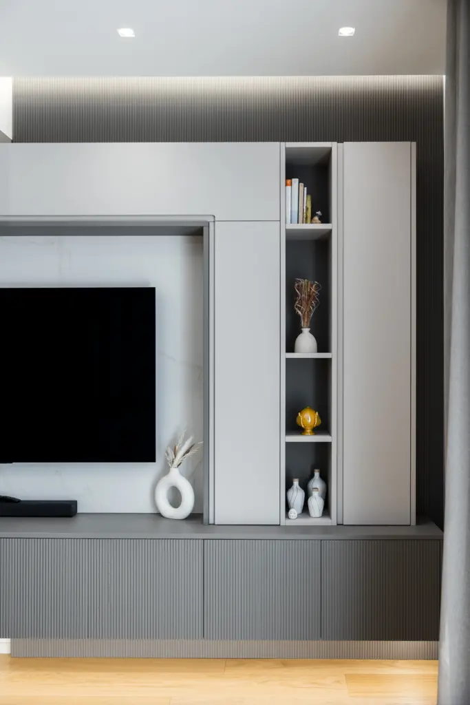 Parete attrezzata moderna su misura con vano per TV, pannello dogato, libreria verticale a giorno e decorazioni di design.
