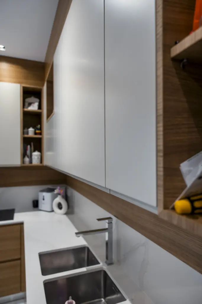 Dettaglio di pensili cucina moderni in legno naturale e bianco opaco con top in marmo.
