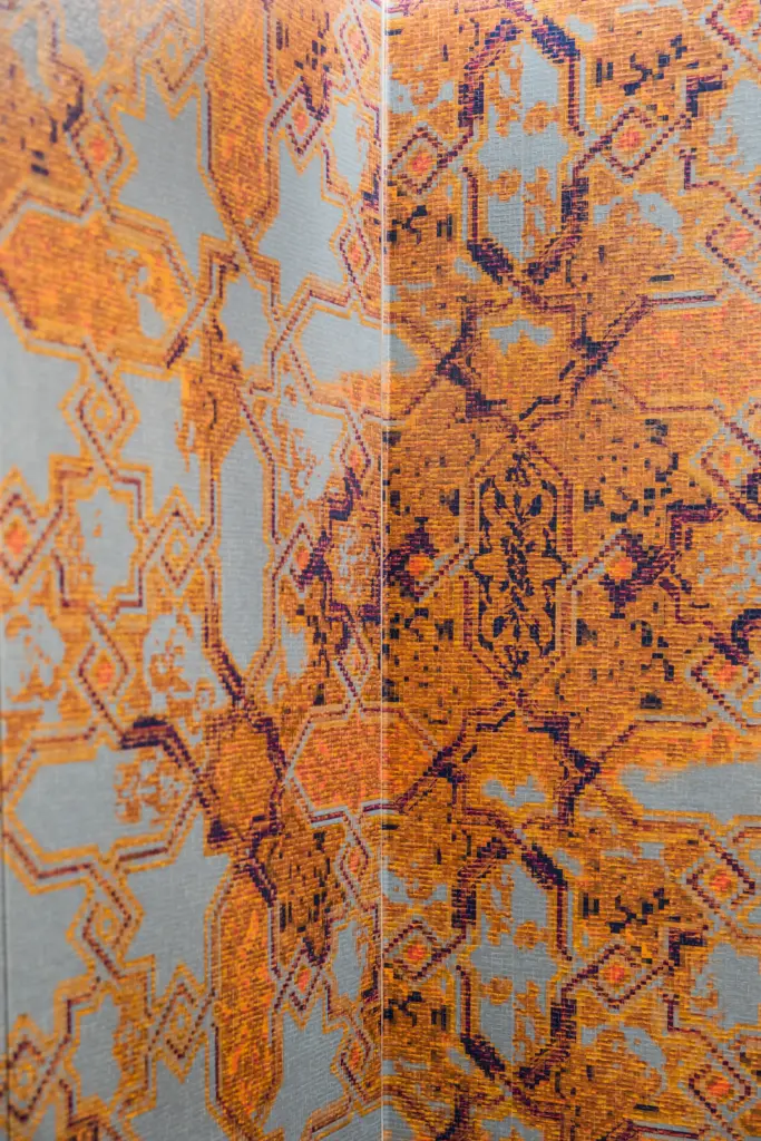 Dettaglio di rivestimento bagno con texture effetto mosaico nei toni dell'arancio e grigio.