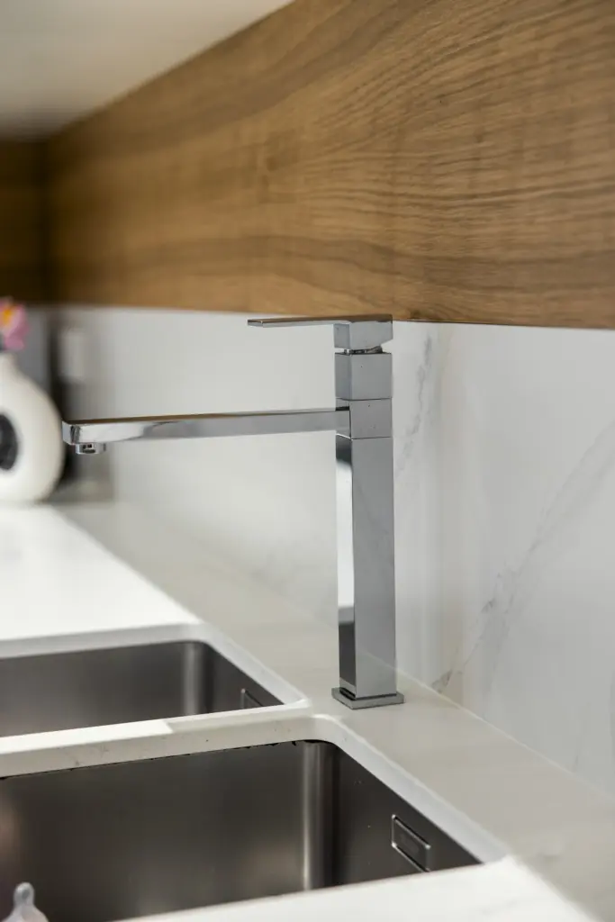 Rubinetto dal design moderno in acciaio inox installato su piano cucina effetto marmo.