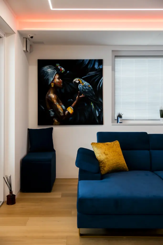Soggiorno moderno con divano blu, illuminazione LED sul soffitto e parete attrezzata bianca.