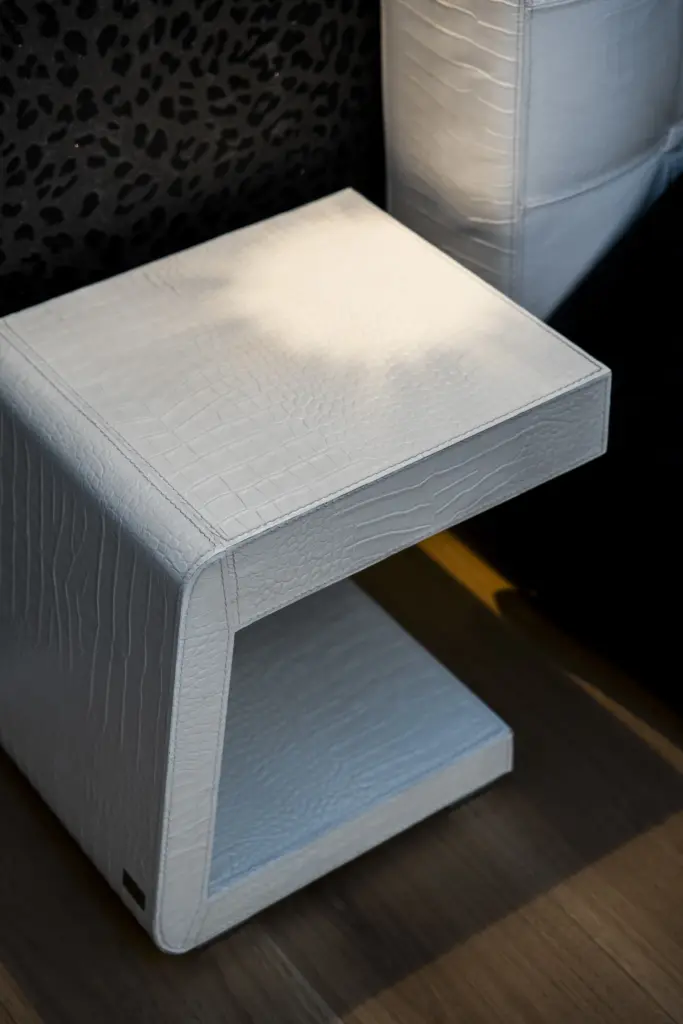 Tavolino di design moderno rivestito in pelle bianca con texture effetto coccodrillo.