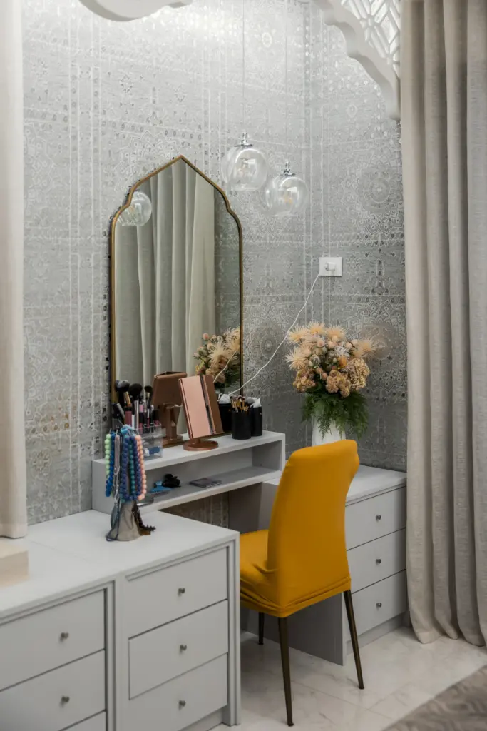 Toeletta bianca su misura con specchio decorativo e sedia gialla, inserita in una cabina armadio di lusso.