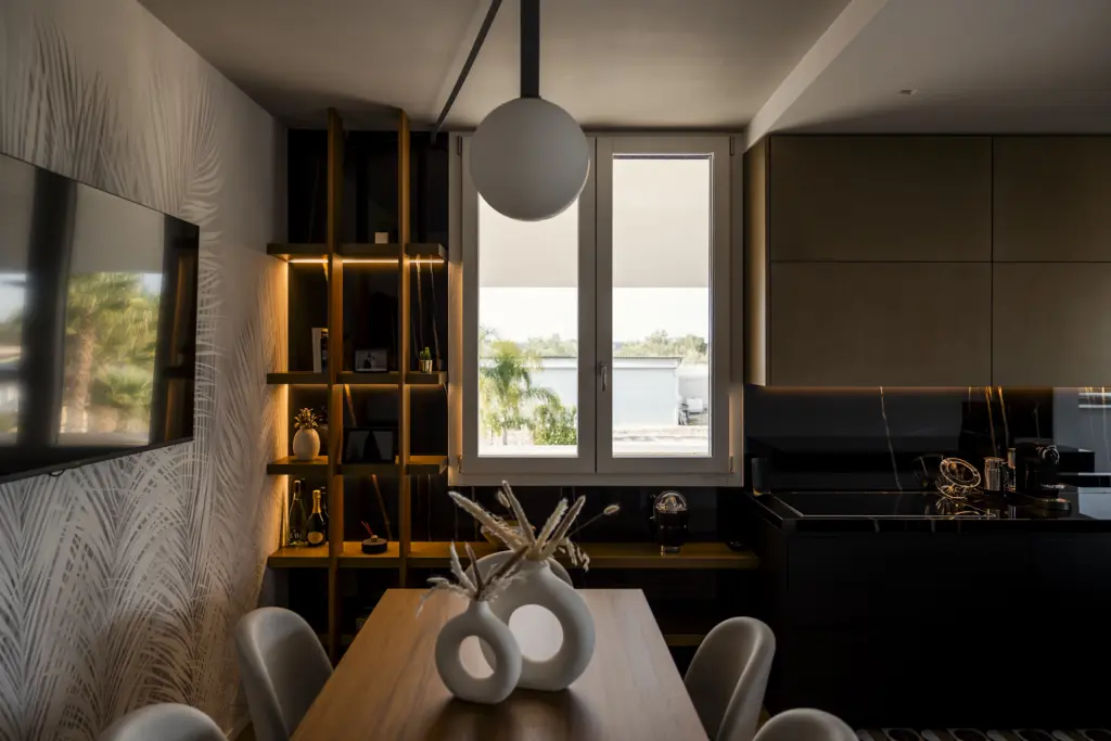 Cucina contemporanea con zona pranzo in legno, libreria verticale retroilluminata e vista su giardino attraverso ampia finestra.
